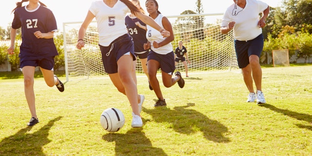 Members Of Female High School Soccer Playing Match