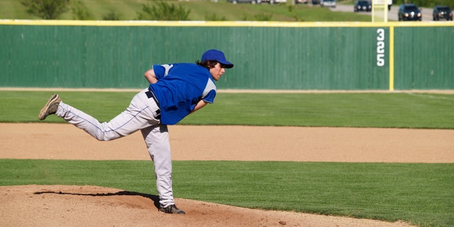 action shot of a high school baseball pitcher winding up to throw the baseball
