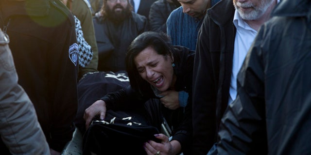 Jan. 3, 2016: Nitza Bakal, mother of Alon Bakal, center, who was killed when a gunman opened fire at a bar in Tel Aviv on Friday, mourn over his body during his funeral in Carmiel, northern Israel.