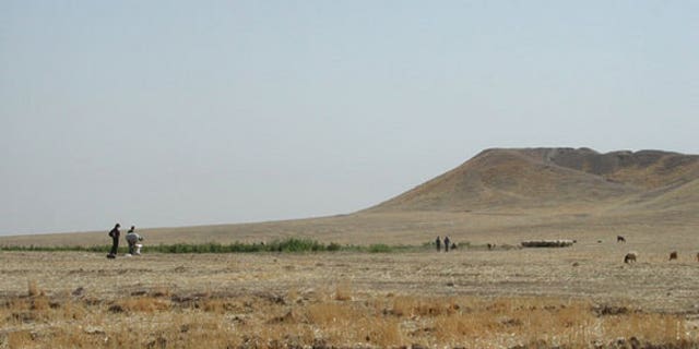 Archaeologists inspect the mound at Tell Brak, in northeastern Syria. The 283 million cubic foot (8 million cubic meter) mound is entirely artificial, accumulating over 6,000 years, as residents built on top of old mud brick buildings.