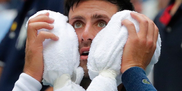 Novak Djokovic, of Serbia, puts an ice towel to his face during a changeover in his match against Marton Fucsovics, of Hungary, during the first round of the U.S. Open tennis tournament.