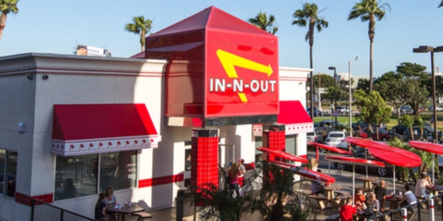 Los Angeles, USA - April 4, 2015: Airplane flying over In-n-Out Burger, LAX, few cars are leaving In-n-out parking lot. People eating outside the restaurant.