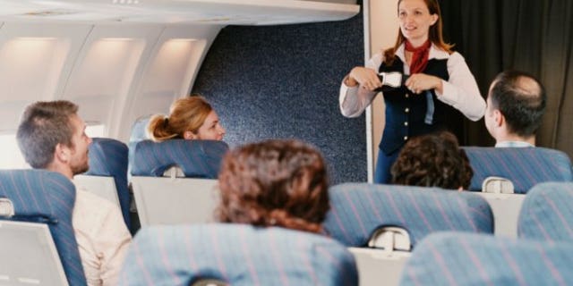 Female Flight Attendant Demonstrating Safety Procedures to Passengers on a Plane