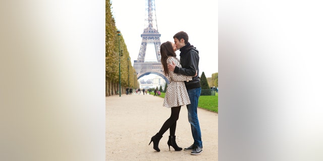 Young romantic couple kissing near the Eiffel Tower in Paris