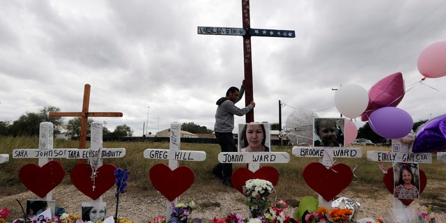 Miguel Zamora strands a cross for the victims of the Sutherland Springs First Baptist Church shooting at a makeshift memorial, Nov. 11, 2017.
