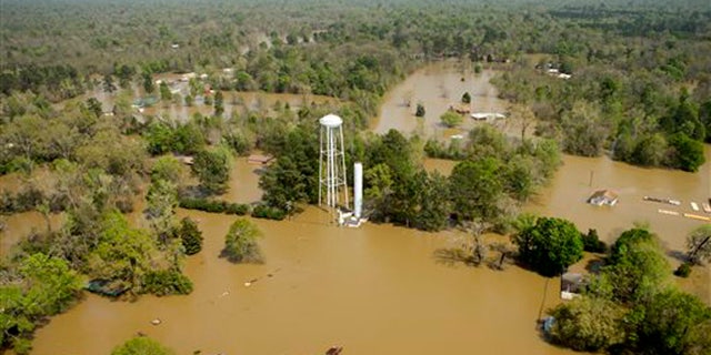 In this aerial photo, homes are surrounded by floodwaters from the nearby Sabine River following recent heavy rains, Tuesday, March 15, 2016, in Deweyville, Texas. (Brett Coomer/Houston Chronicle via AP) MANDATORY CREDIT