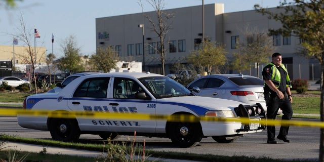 A police officer stops a vehicle at a check point in front of a FedEx distribution center where a package exploded, Tuesday, March 20, 2018, in Schertz, Texas.