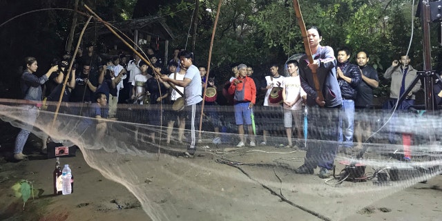 Relatives hold fishing nets, as a symbol to fish out lost spirits inside cave, as a group of locals and relatives perform a ritual calling for those are missing at the entrance of the cave, Tuesday, June 26, 2018, in Mae Sai, Chiang Rai province, northern Thailand.