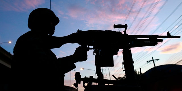 May 20, 2014: A Thai soldier mans his machine gun atop a military vehicle outside the Centre for the Administration of Peace and Order (CAPO) after soldiers were sent in the center in Bangkok, Thailand.