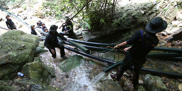Thai soldiers drag water pipes that will help bypass water from entering a cave where 12 boys and their soccer coach have been trapped since June 23, in Mae Sai, Chiang Rai province, in northern Thailand, July 7, 2018.