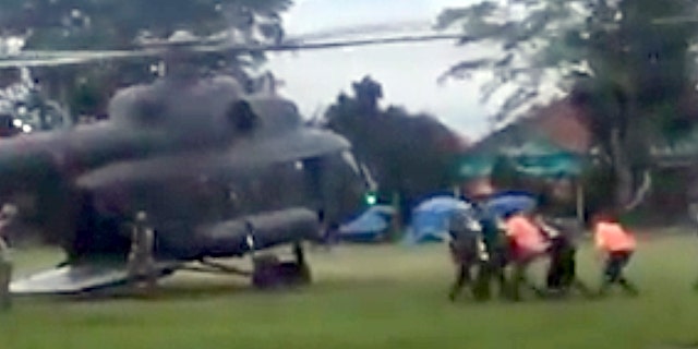 In this image made from video taken Sunday, July 8, 2018, an emergency team carries a stretcher carrying one of the rescued boys from the flooded cave to a waiting helicopter in Mae Sai, Chiang Mai province, northern Thailand.