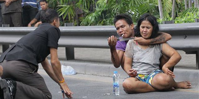 April 5, 2012: A Thai policeman talks to Sakdawut Hamsiri, 30, who holds a knife against his wife Thawee Naiyanit on a street in Bangkok.