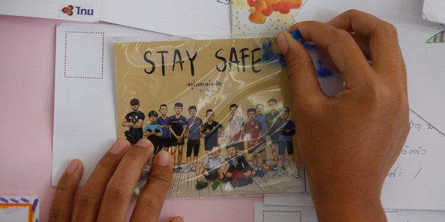 A Thai well wisher puts a poster to pray for boys and their soccer coach.