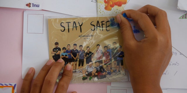 A Thai well wisher puts a poster to pray for boys and their soccer coach.