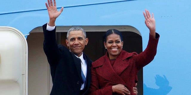 Former President Barack Obama waves with his wife Michelle as they board Special Air Mission 28000, a Boeing 747 which serves as Air Force One, at Joint Base Andrews, Maryland, Jan. 20, 2017.