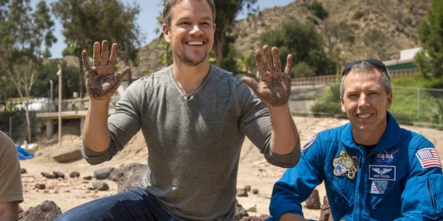 Actor Matt Damon (C) who stars as NASA Astronaut Mark Watney in the film 'The Martian' smiles after having made his hand prints in cement at the Jet Propulsion Laboratory (JPL) Mars Yard, while NASA Astronaut Drew Feustel look on in Pasadena, California in this August 18, 2015.