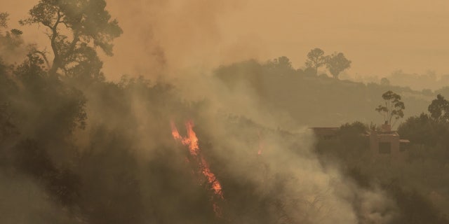 In this photo provided by the Santa Barbara County Fire Department, pockets of unburned vegetation flare up off Bella Vista Dr. in Montecito, Calif., Wednesday, Dec. 13, 2017. After announcing increased containment on the Thomas fire, one of the biggest wildfires in California history, officials Wednesday warned that communities remain at risk and the threat could increase as unpredictable winds whip up again. (Mike Eliason/Santa Barbara County Fire Department via AP)