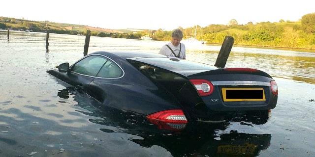 This picture shows the moment an expensive Jaguar was consumed by water - after the owner left the car parked on a tidal road. See SWNS story SWJAG; The black Jaguar XK, which cost around £60,000 when new, can be seen with the boot open and water nearly to the top of the windows. Chris and Gill Freeborn were passing in their boat when they spotted the unfortunate situation, and quickly took some snaps. Gill said the sight made her "howl with laughter", and Chris said the Jaguar was "clearly not a happy pussy cat". The car, worth around £10,000 on the current market, has now been removed from Aveton Gifford tidal road in Kingsbridge, Devon.