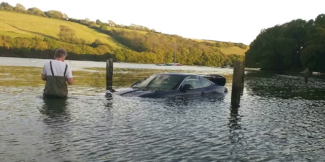 This picture shows the moment an expensive Jaguar was consumed by water - after the owner left the car parked on a tidal road. See SWNS story SWJAG; The black Jaguar XK, which cost around £60,000 when new, can be seen with the boot open and water nearly to the top of the windows. Chris and Gill Freeborn were passing in their boat when they spotted the unfortunate situation, and quickly took some snaps. Gill said the sight made her "howl with laughter", and Chris said the Jaguar was "clearly not a happy pussy cat". The car, worth around £10,000 on the current market, has now been removed from Aveton Gifford tidal road in Kingsbridge, Devon.