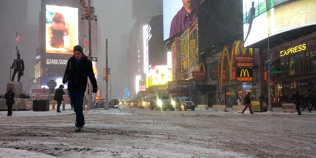 Pedestrians walk through snow-covered streets in Times Square in New York as a powerful "bomb cyclone" hits the Northeast.
