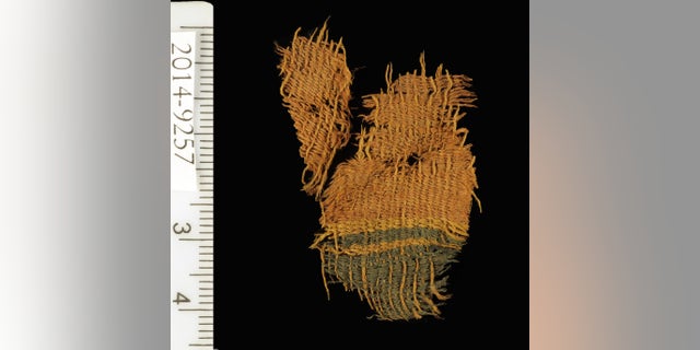Fine wool textile dyed red and blue. The textile used the varying colors of natural animal hair to create black and orange-brown colors for decorative bands. (Clara Amit, courtesy of the Israel Antiquities Authority)