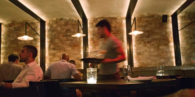June 12, 2013: A server clears dishes from a table inside a New York restaurant.