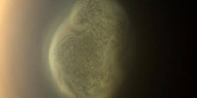 June 27, 2012: This true color image captured by NASA's Cassini spacecraft before a distant flyby of Saturn's moon Titan shows a south polar vortex swirling in the moon's atmosphere.