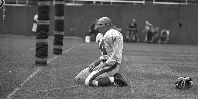 In this Sept. 20, 1964, file photo, New York Giants' Y.A. Tittle squats on the field after being hit hard while passing during a game against the Pittsburgh Steelers, in Pittsburgh