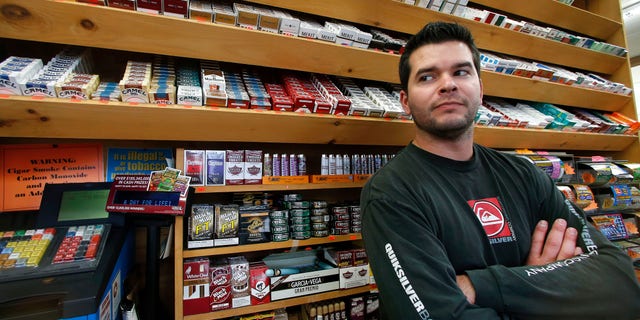 Nov. 6, 2014: Brian Vincent poses in front of a large display of tobacco products at Vincent's Country Store in Westminster, Mass.