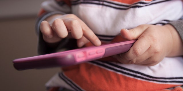 toddler playing with an iphone istock medium