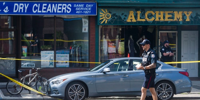 Police are photographed investigating a car with a bullet hole within the scene of a mass shooting in Toronto on Monday, July 23, 2018.