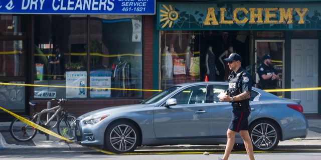 Police are photographed investigating a car with a bullet hole within the scene of a mass shooting in Toronto on Monday, July 23, 2018.