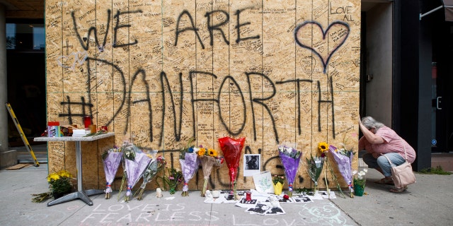 A woman writes a message on a makeshift memorial.