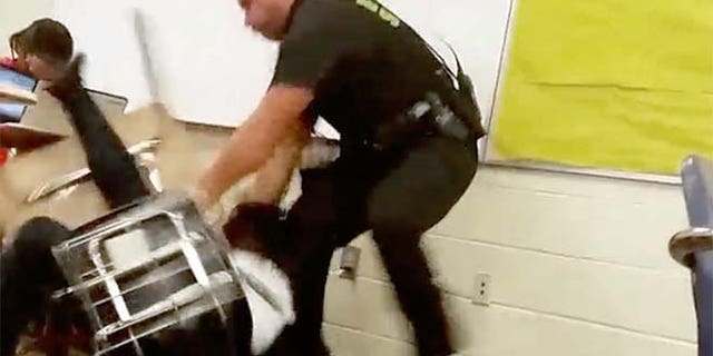 In this Monday, Oct, 26, 2015 photo made from video taken by a Spring Valley High School student, Senior Deputy Ben Fields tries to forcibly remove a student who refused to leave her high school math class, in Columbia S.C. The Justice Department opened a civil rights investigation Tuesday after Fields flipped the student backward in her desk and tossed her across the floor. (AP Photo)