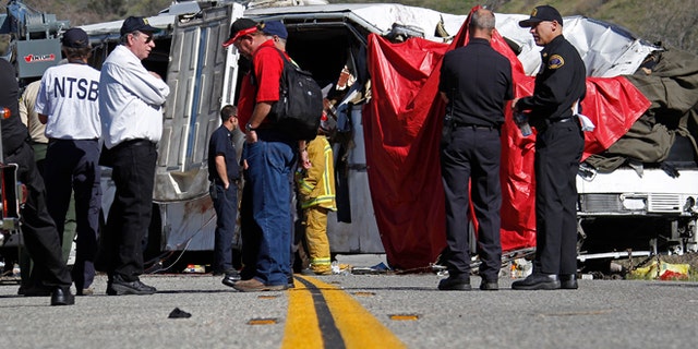 Feb. 4: Investigators stand at the scene after a tour bus was lifted back onto the road after it collided with two other vehicles and crashed, killing at least eight people and injuring 38, just north of Yucaipa, Calif.