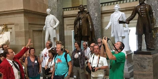 A tour guide talks to tourists inside the Capitol's Statuary Hall on Thursday near the statue of Jefferson Davis (center, in bronze).