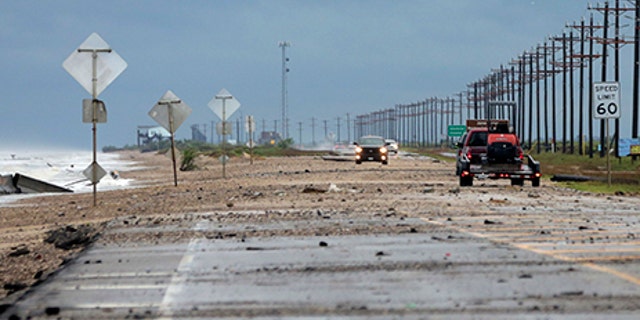 Vehicles navigate past waves and debris washing over in High Island, Texas, as Tropical Storm Cindy approaches Wednesday, June 21, 2017.