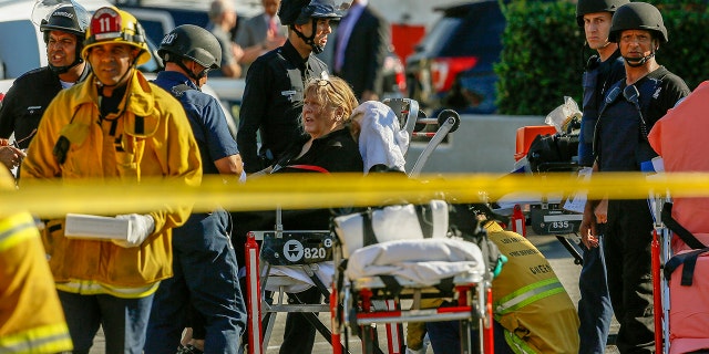 An unidentified woman is helped by paramedics at a triage area after a gunman held dozens of people hostage inside a Trader Joe's store in Los Angeles, July 21, 2018.