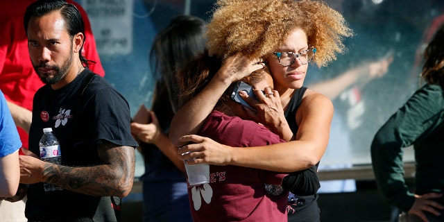 Unidentified Trader Joe's supermarket employees hug after being evacuated by Los Angeles Police after a gunman barricaded himself inside the store in Los Angeles, July 21, 2018.