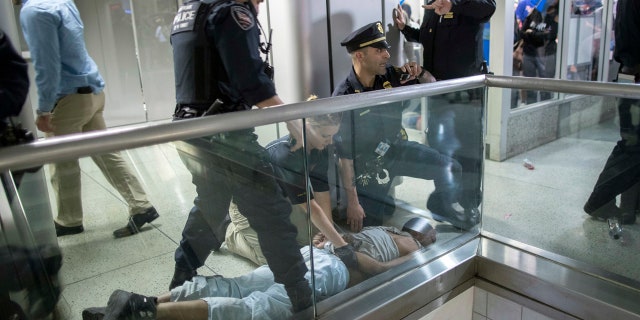 New York City police officers detain a passenger from a disabled New Jersey Transit train who became belligerent and sparked a stampede among passengers leaving the overcrowded station once the train finally arrived at New York's Penn Station, Friday, April 14, 2017.