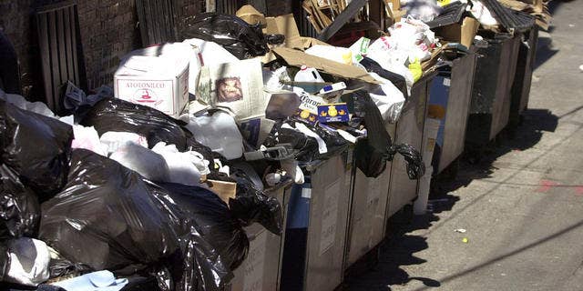 Trash overflows from dumpsters behind an apartment building. (AP)