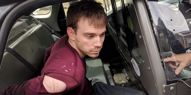 In this photo released by the Metro Nashville Police Department, Travis Reinking sits in a police car after being arrested in Nashville, Tenn., on Monday, April 23, 2018.