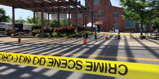 Police crime-scene tape keeps people away from the brick Roebling Wire Works building, background, in Trenton, N.J., hours after a shooting broke out there at an all-night art festival.