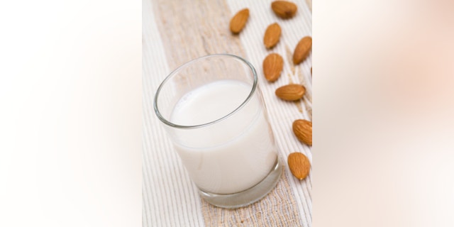 Almond milk in glass with almonds
