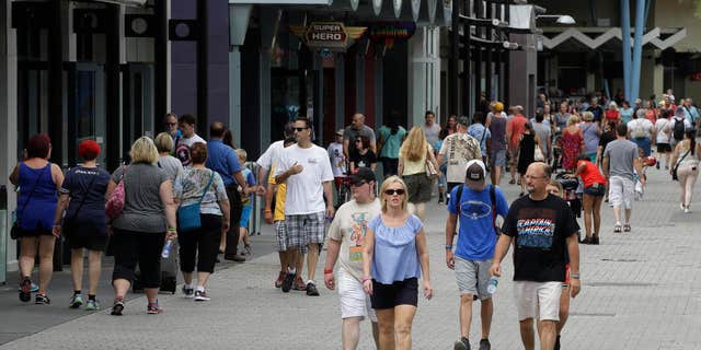 In this Tuesday, Sept. 13, 2016 photo, tourists stroll by the shops and restaurants at the Disney Spring complex in Lake Buena Vista, Fla. Hotel occupancy rates in the Orlando area are down about 2.5 percent for the year through July