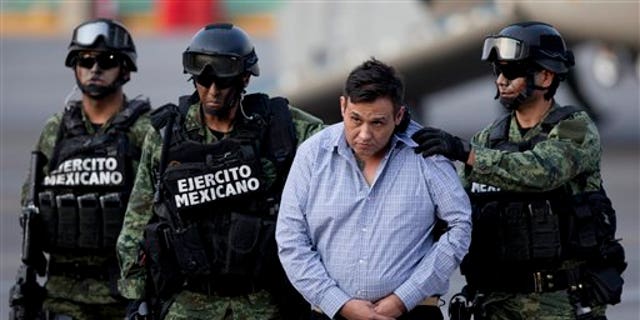 Soldiers escort a man who authorities identified as Omar Trevino Morales, alias "Z-42," leader of the Zetas drug cartel, as he is moved from a military plane to a military vehicle at the Attorney General's Office hangar in Mexico City, Wednesday, March 4, 2015. An official who was not authorized to be quoted by name because of government policy, said Morales was arrested on Wednesday in a pre-dawn raid in San Pedro Garza Garcia, a wealthy suburb of the northern city of Monterrey. (AP Photo/Eduardo Verdugo)