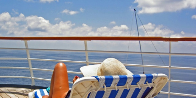 A woman sits on the upper deck of a cruise ship and overlooks the ocean