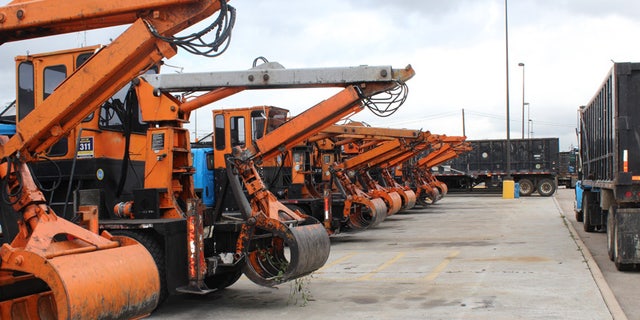 A row of debris scooper trucks in Houston, waiting to go out in the field.