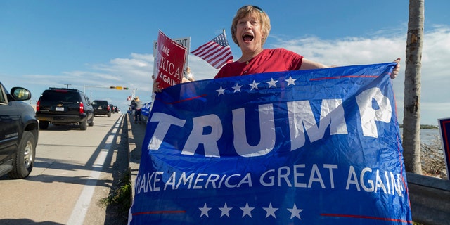 Mary Jude Smith cheers for President Donald Trump as his motorcade passes by on Southern Blvd. enroute to his Mar-a-Lago estate from Trump International Golf Club, Thursday, Dec. 28, 2017, in West Palm Beach, Fla. (Greg Lovett/Palm Beach Post via AP)