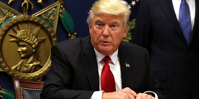 U.S. President Donald Trump signs an executive order to impose tighter vetting of travelers entering the United States, at the Pentagon in Washington, U.S., January 27, 2017. The executive order signed by Trump imposes a four-month travel ban on refugees entering the United States and a 90-day hold on travelers from Syria, Iran and five other Muslim-majority countries. Picture taken January 27, 2017. REUTERS/Carlos Barria - RTSXWM6